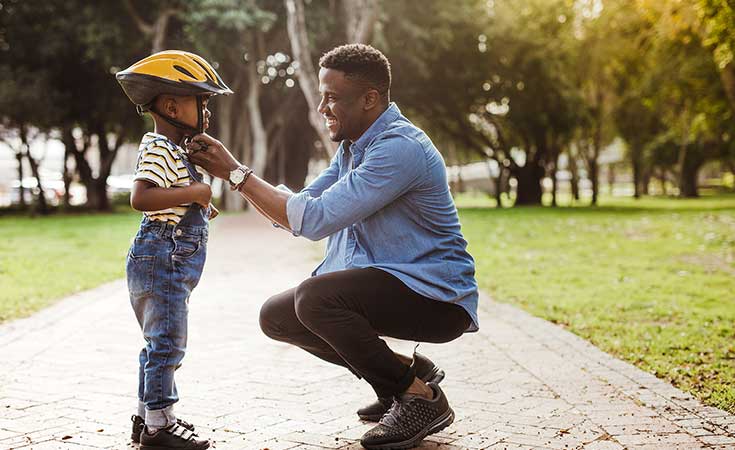 father buckling bike helmet on his son