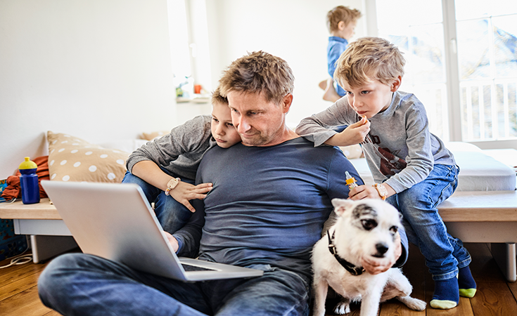 Dad on laptop with sons and dog