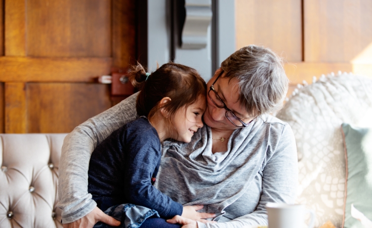 Lady hugging a child sitting on a sofa