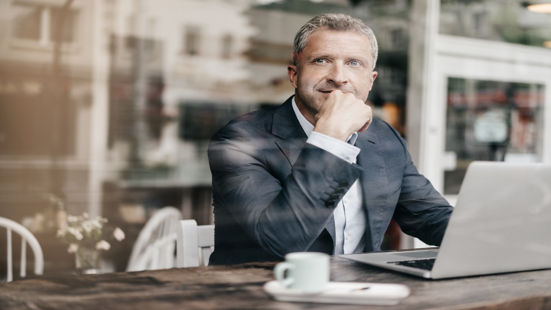 Man in coffee shop with laptop plans his retirement investment portfolio